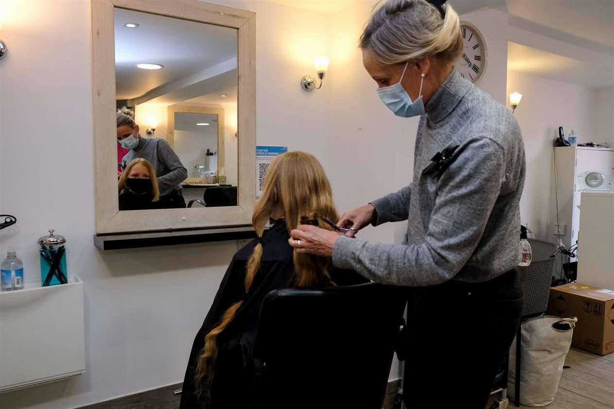 A hairdresser cuts Bertie's hair.