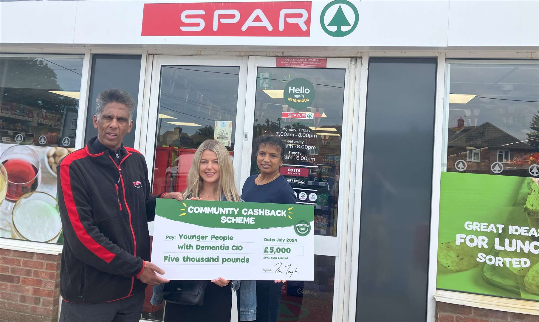 Ex-subpostmaster Hash Shingadia and his wife Chandrika presenting the cheque to Amy Pagan, Marketing, Fundraising and Social Media Assistant at Younger People with Dementia, outside his Upper Bucklebury store