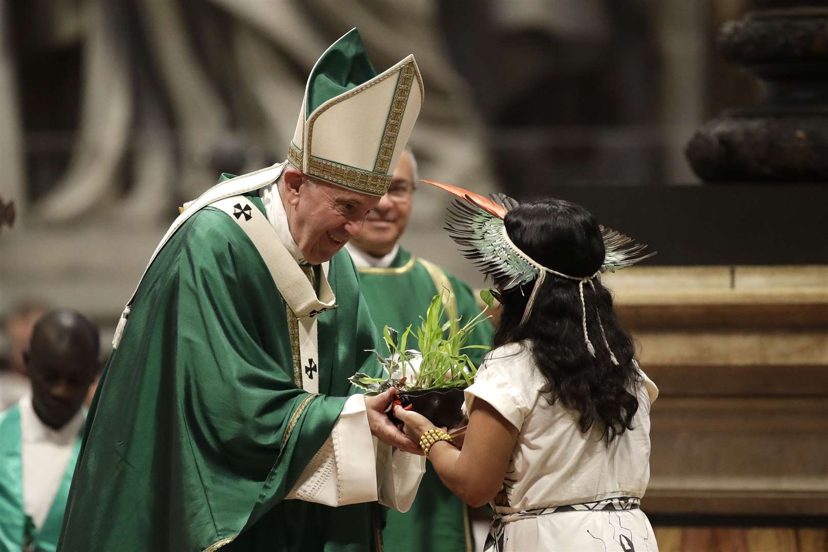 An Amazonian indigenous girl gives Pope Francis a plant during the offertory of a mass in 2019 Alessandra Tarantino/AP)