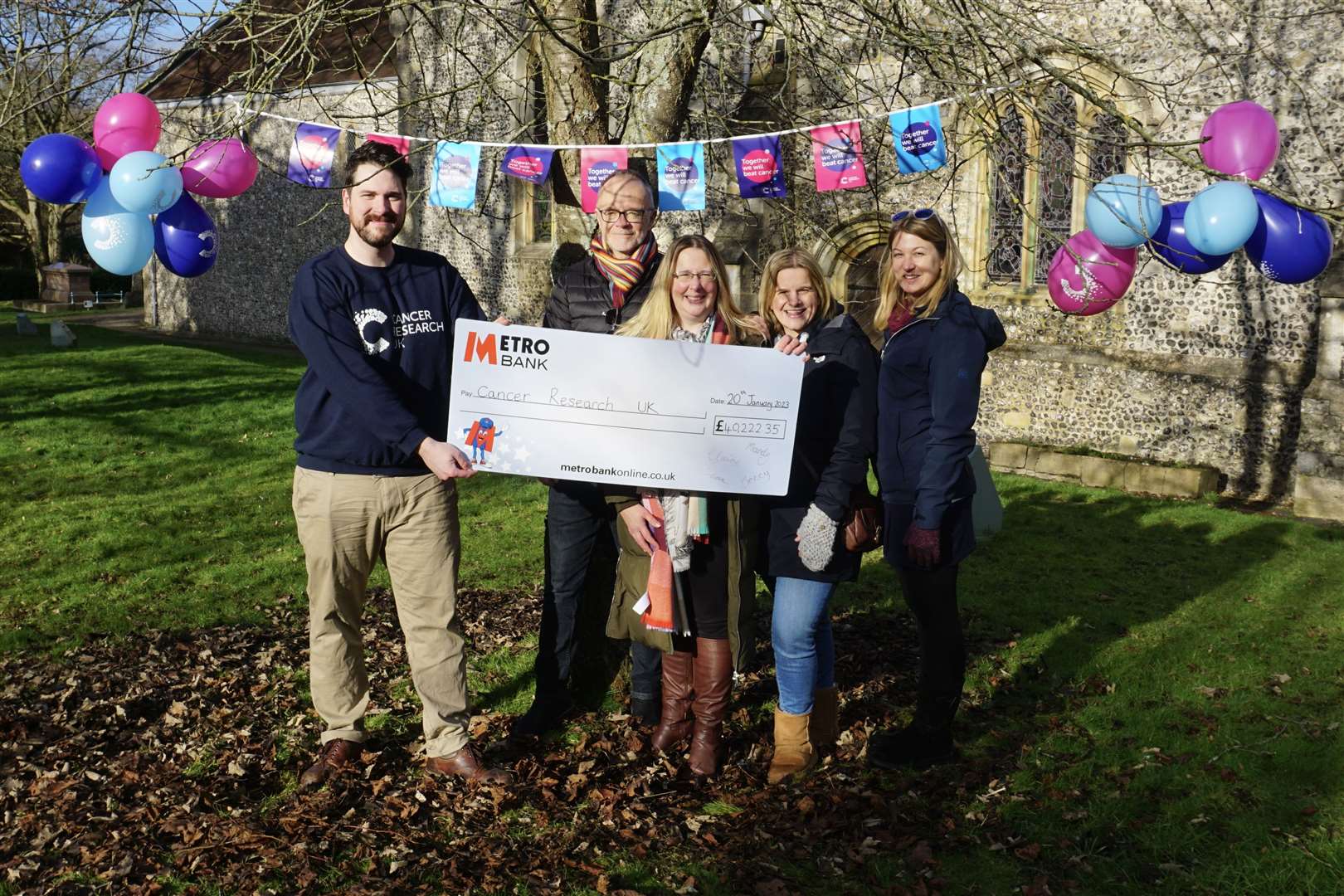 The group presenting a cheque for £40,222.35 to a Cancer Research UK representative