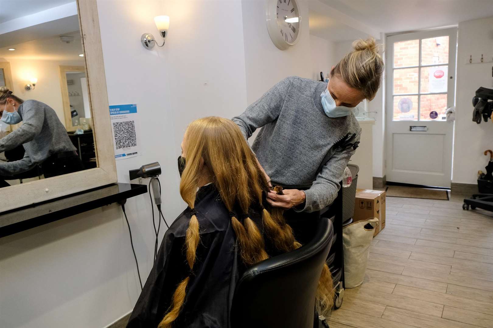 A hairdresser cuts Bertie's hair.