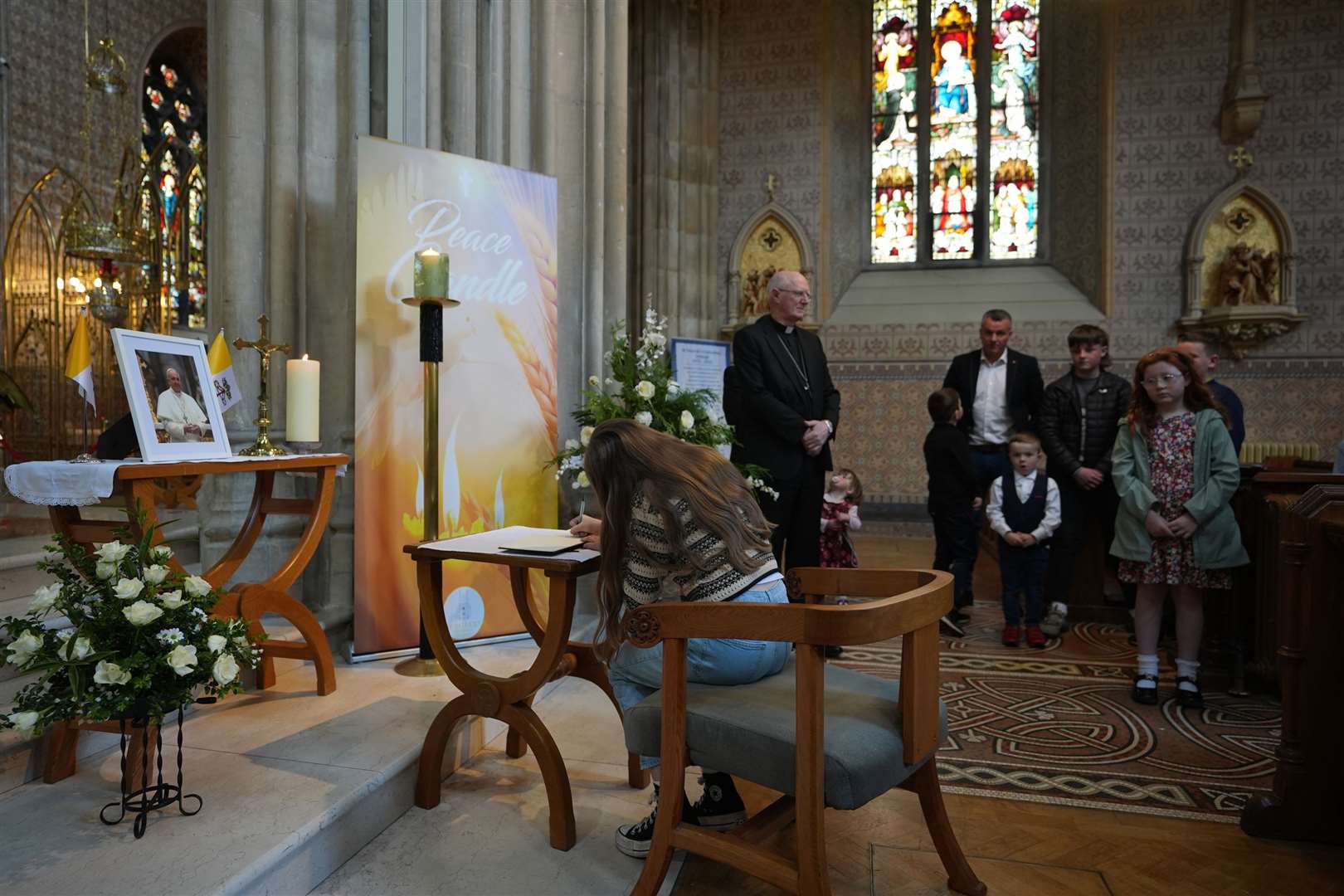 A woman signs a book of condolence for Pope Francis at St Patrick’s Cathedral in Armagh (Niall Carson/PA)