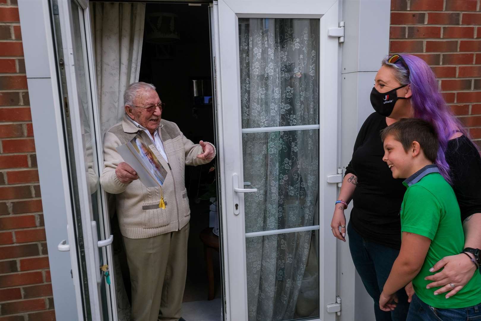 John Quince, age 100, shows his granddaughter Jamilee Dooley and great-grandson Connor Dooley-Jones, age 9, his card from the Queen Picture Phil Cannings