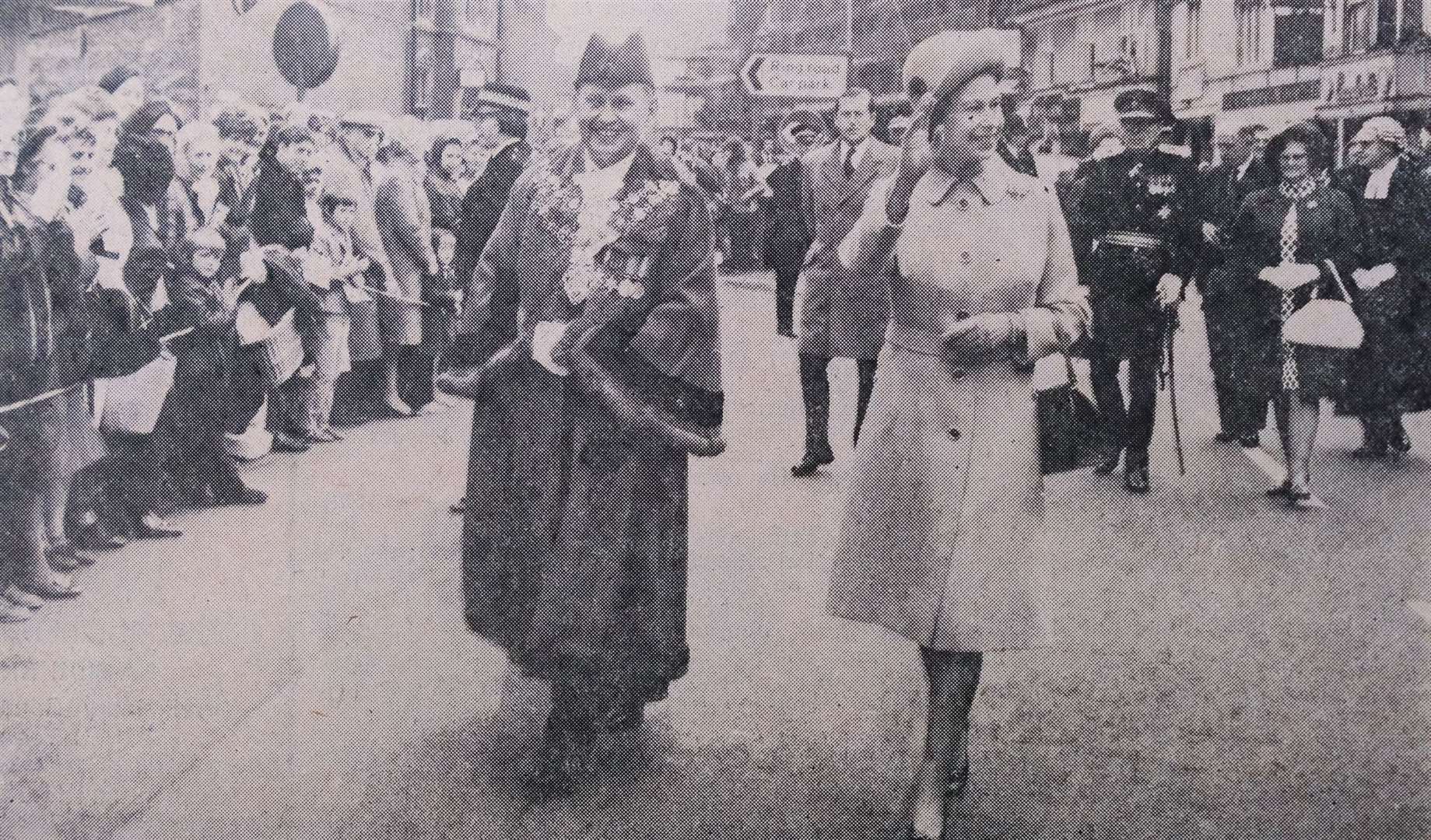 Walking through Market Place accompanied by Wilfred Cannings