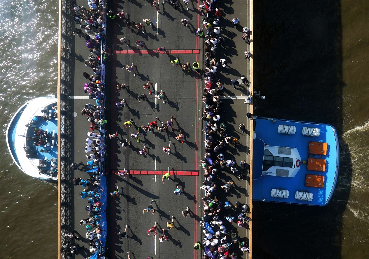 A large boat goes under Tower Bridge as the mass participation race goes by (Jonathan Brady/PA)