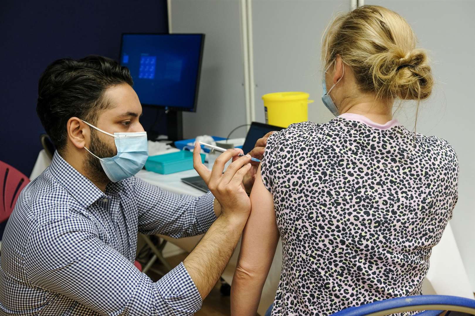 A vaccination worker injects a patient.
