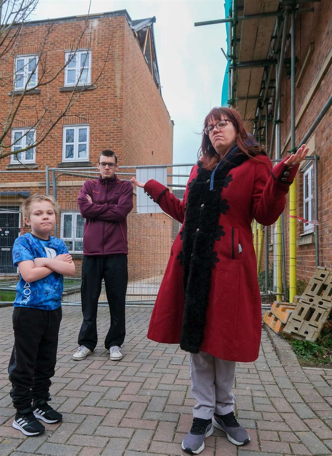 Mrs Wilkins with sons Adam Wilkins, 8, and Oliver Walls, 21, in front of their house