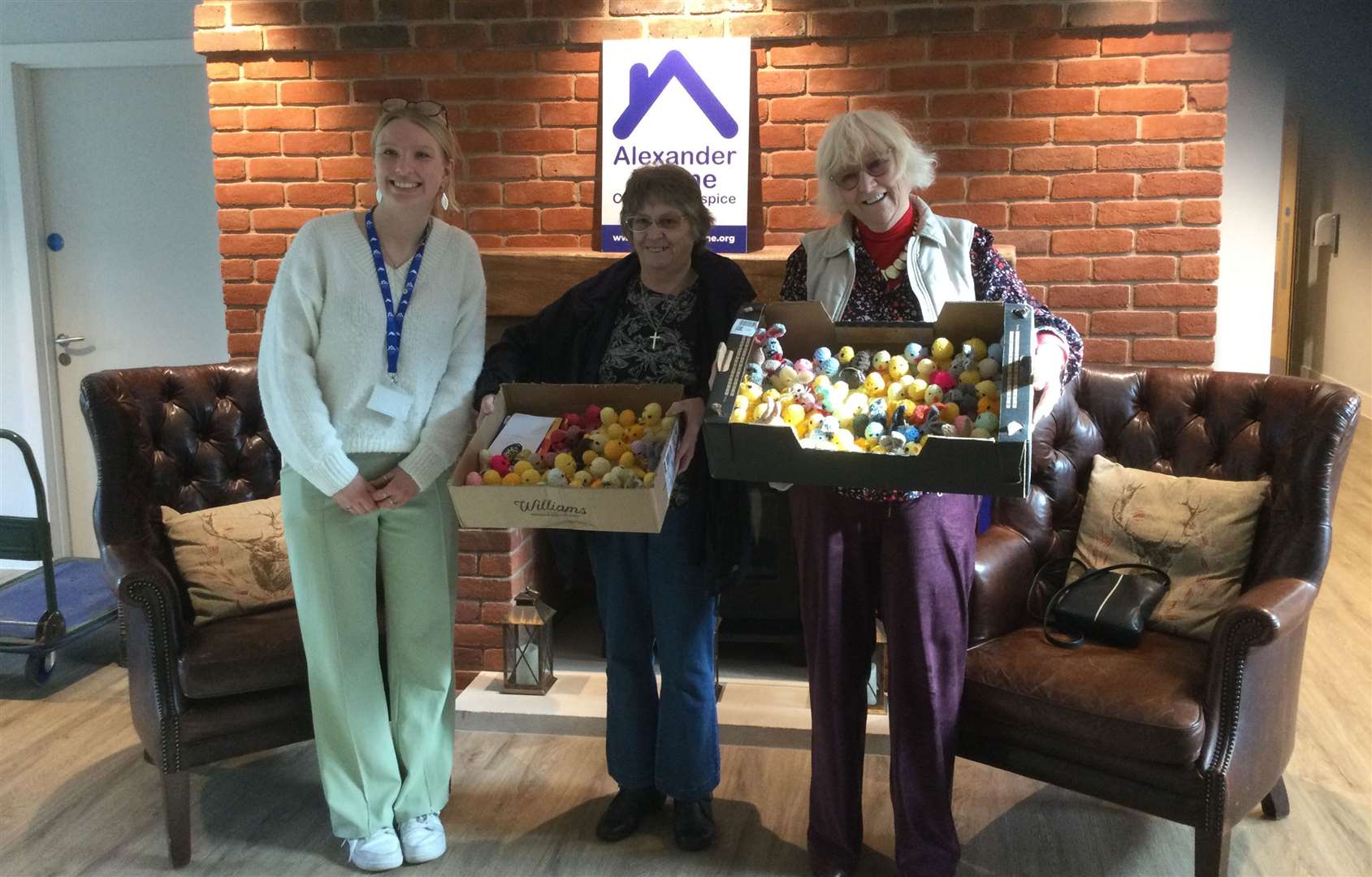 Hannah Pickup from Alexander Devine Hospice receiving the knitted goods from Patsy Stone and Diane Kersey from Warm Welcome