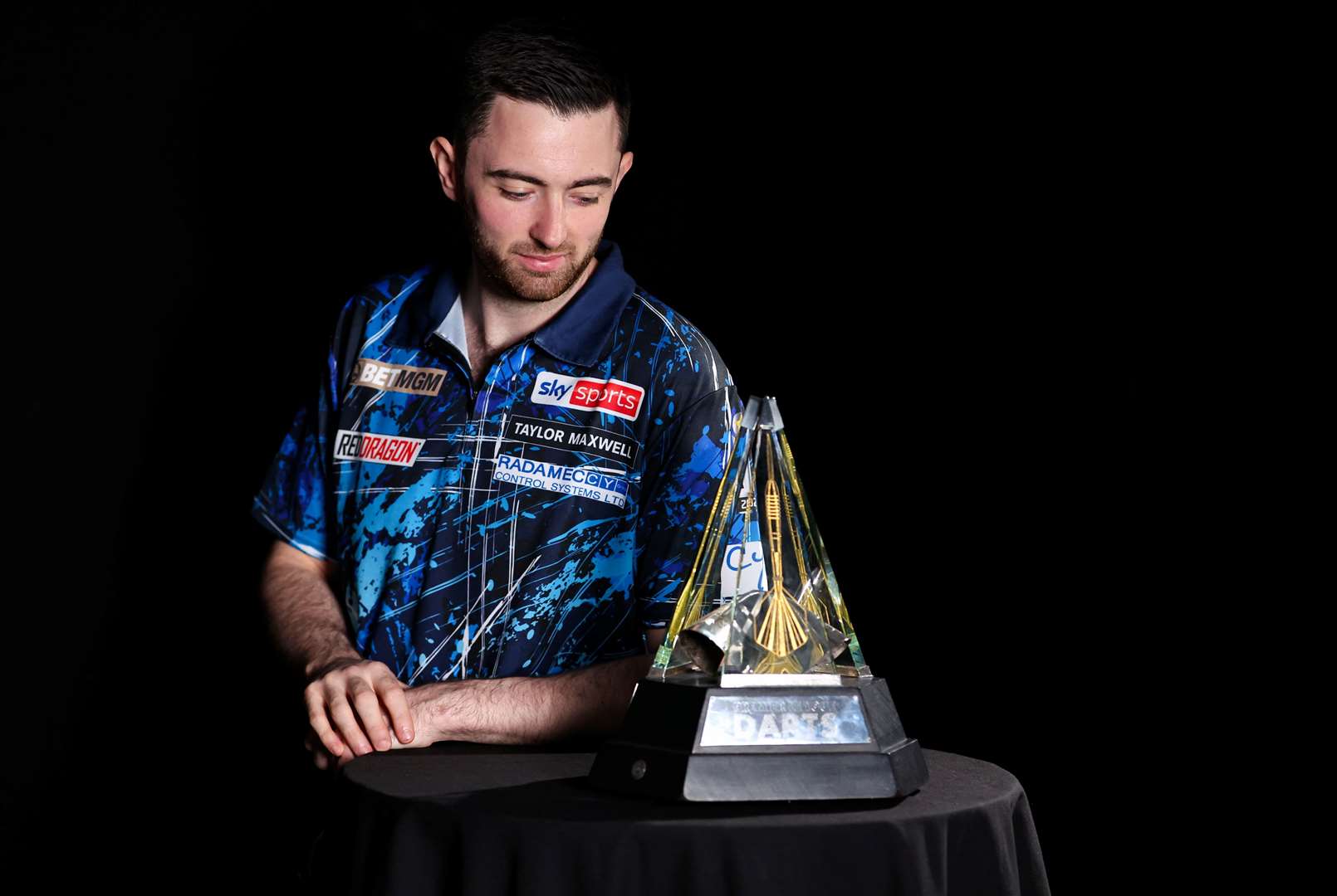 Luke Humphries examines the BetMGM Premier League trophy - (Kieran Cleeves/PDC)