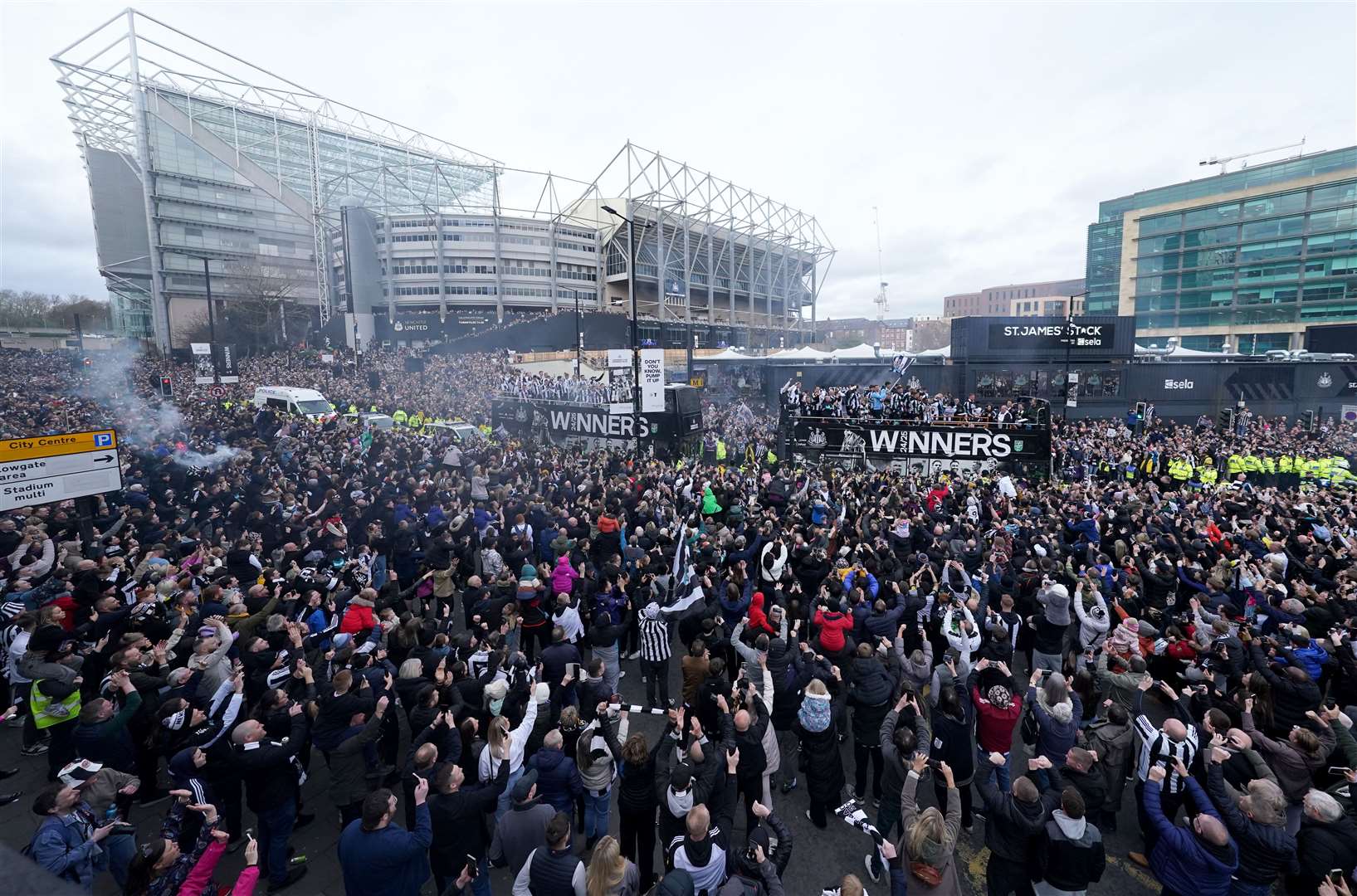 The open top buses carrying the Newcastle United players pass by fans outside St James’ Park during the Carabao Cup trophy parade in Newcastle (Owen Humphreys/PA)