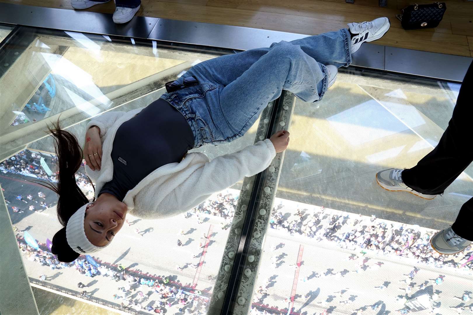 A visitor to Tower Bridge lays on the glass walk (Jonathan Brady/PA)
