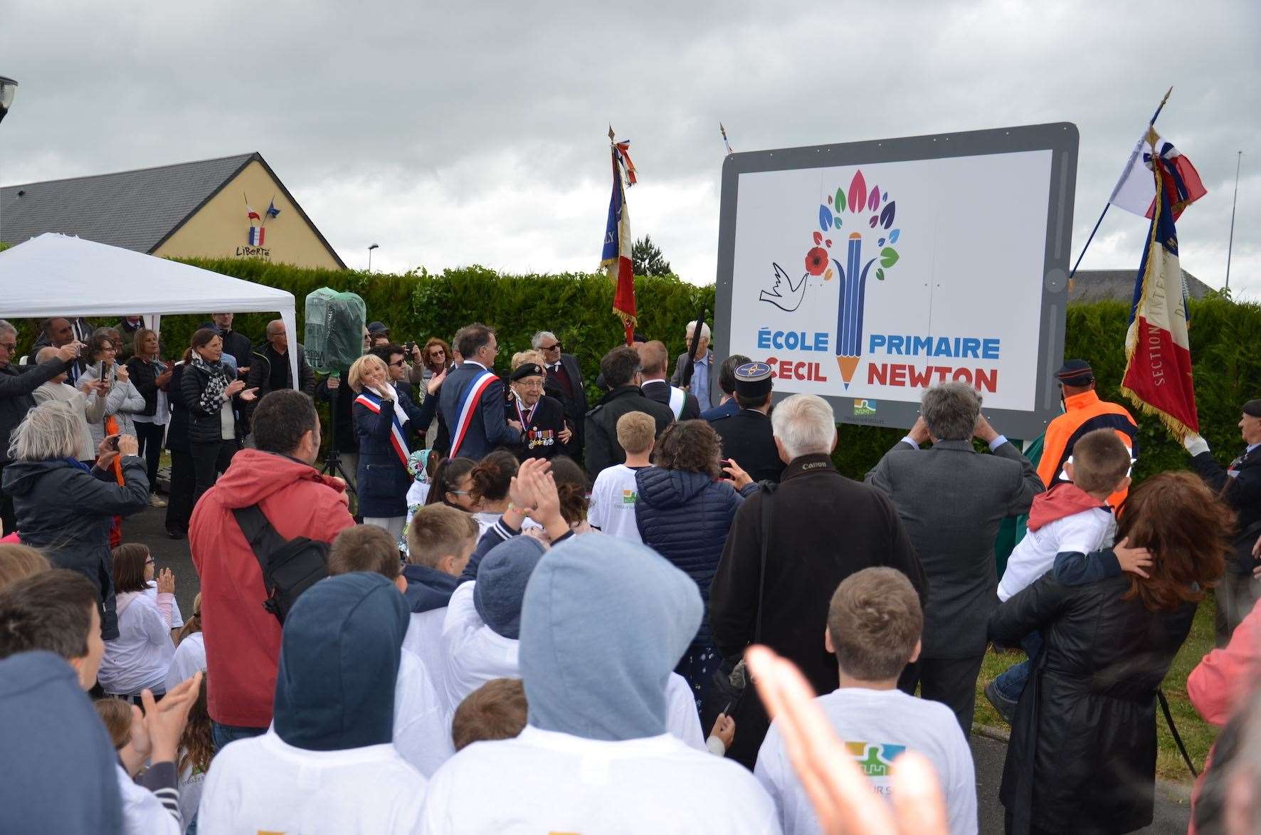 Cecil Newton attending the school's renaming ceremony in 2018, standing beside the Mayor of Creully sur Seulles Thierry Ozenne, left