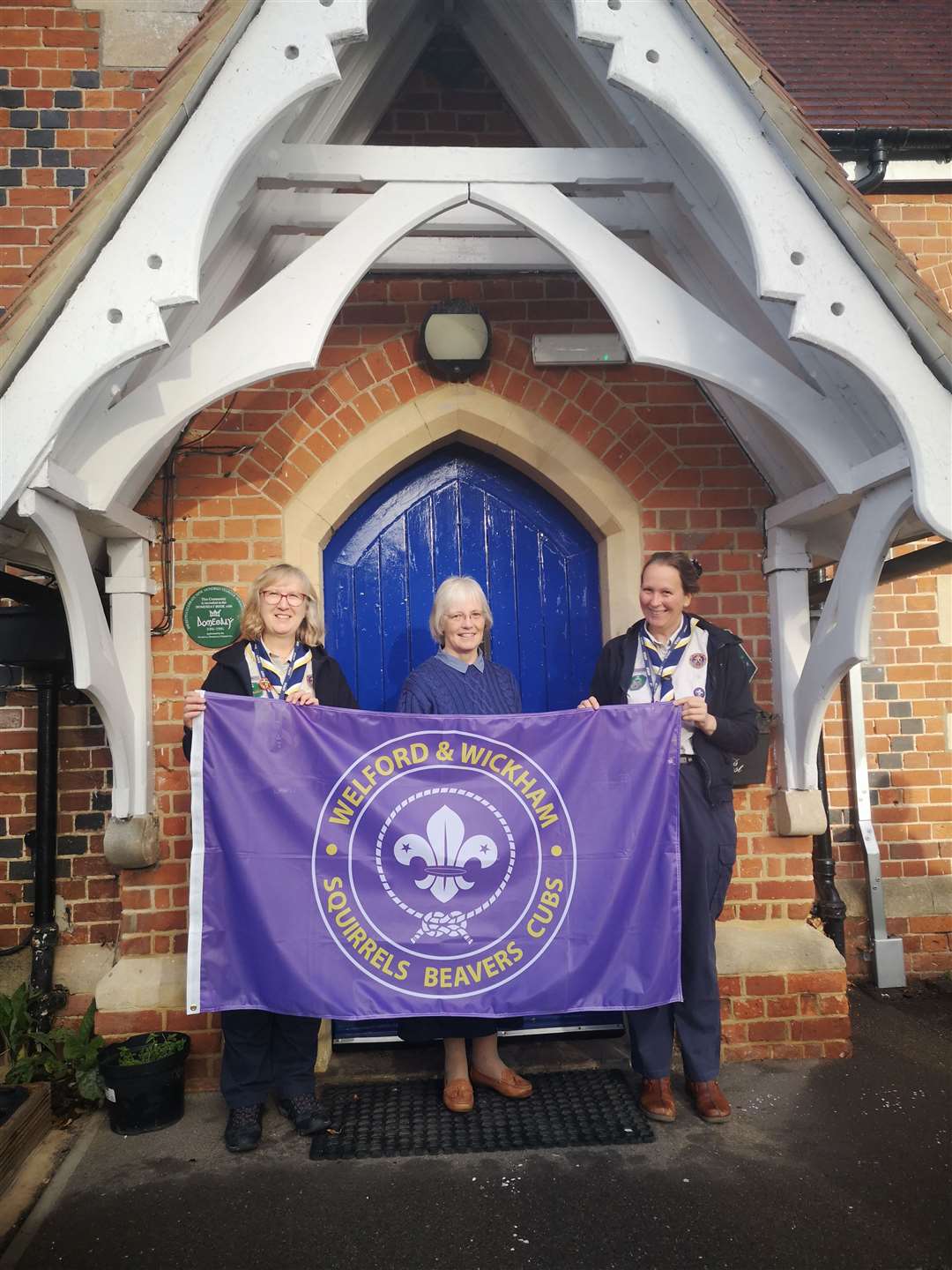 Headteacher Mrs Valentine, Mrs Willis and Mrs Kennedy with the flag outside the school