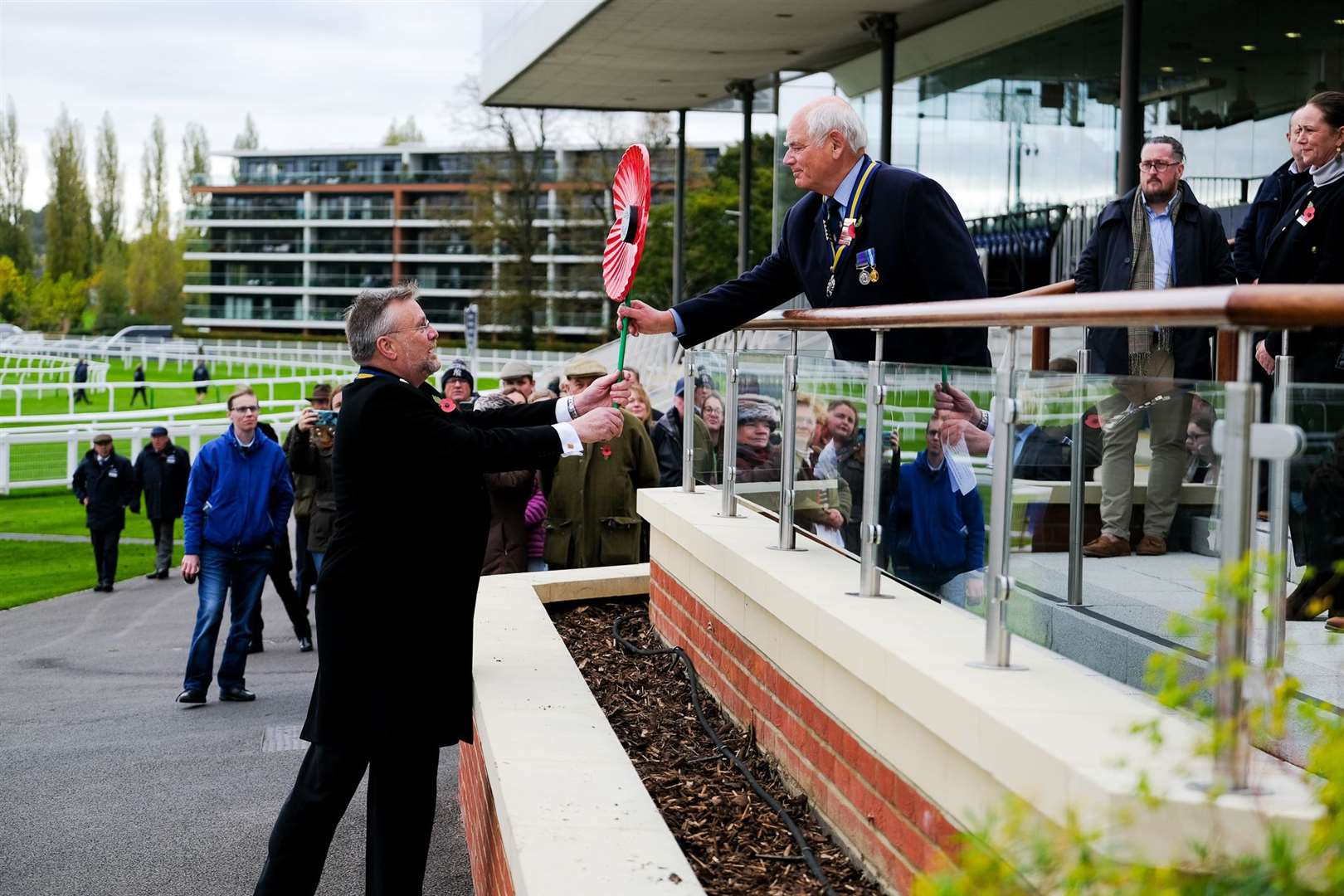 The poppy is handed over to Group Captain David Drew, but Major Jim Sibbald