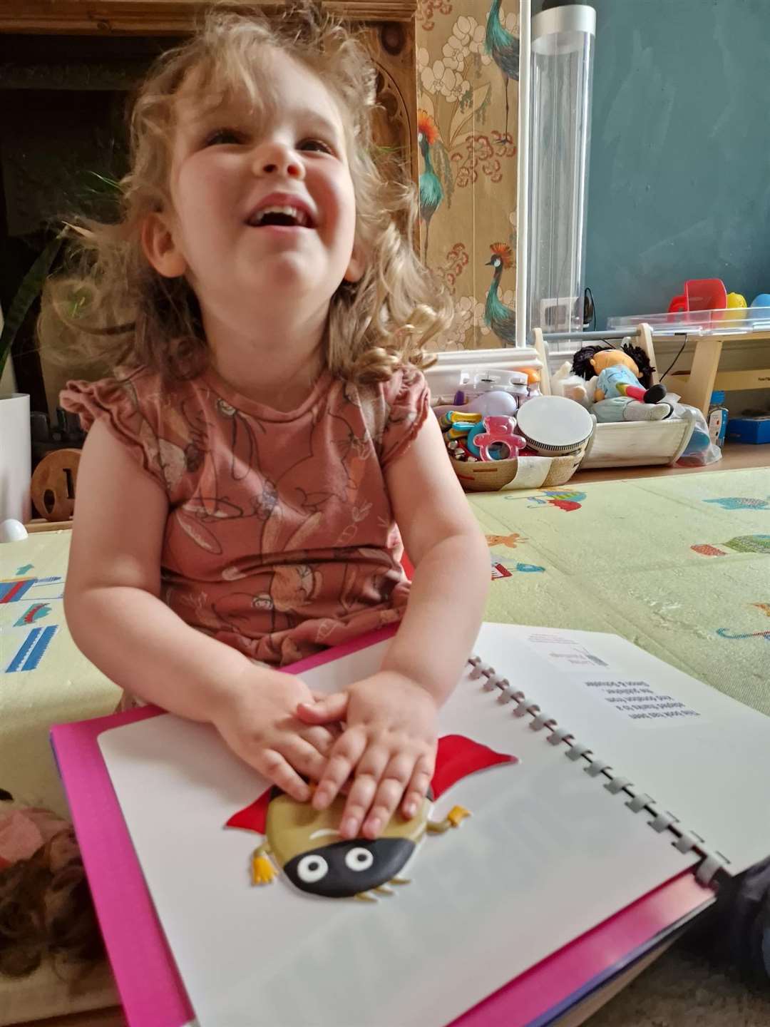 Mia, 4, a visually impaired Living Paintings service user explores a tactile-audio version of the children's book Supertato
