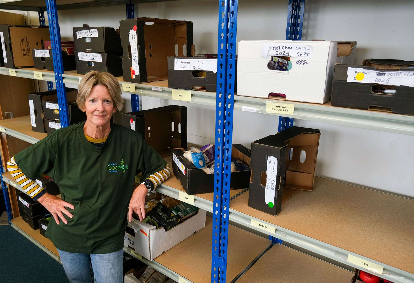 Lead Volunteer, Ruth Winter, standing by the empty shelves at West Berks Foodbank