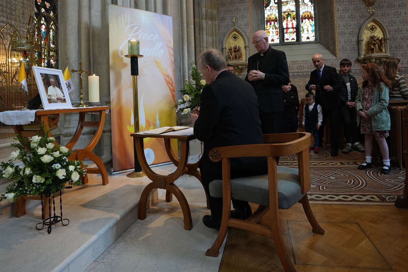 The Archbishop of Armagh, Eamon Martin, watched by Archbishop Dermot Farrell Archbishop of Dublin, signs a book of condolences for Pope Francis (Niall Carson/PA)