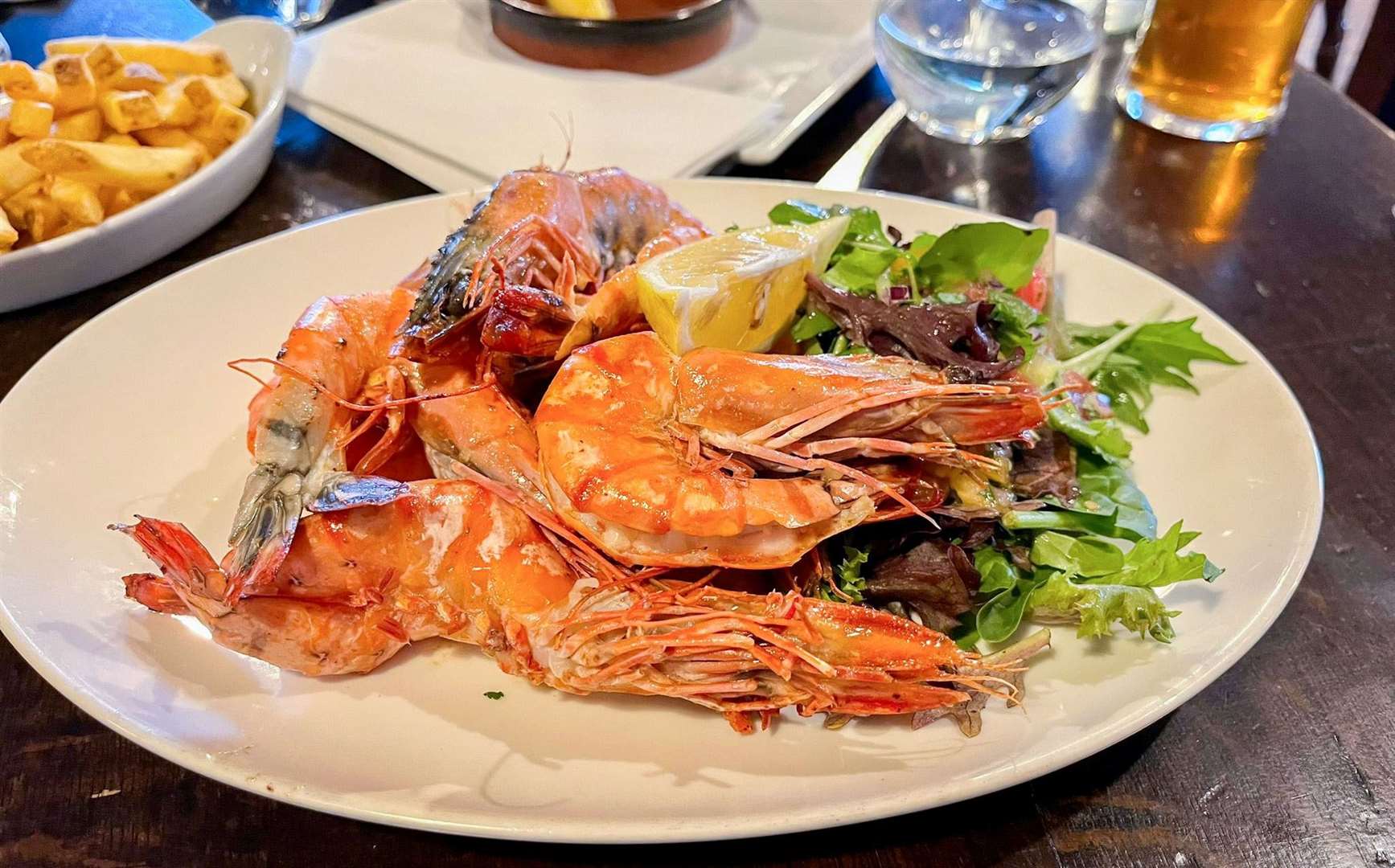 Six Queen Prawns, butterflied and grilled in lemon and garlic butter, house mixed salad, fries (£28)