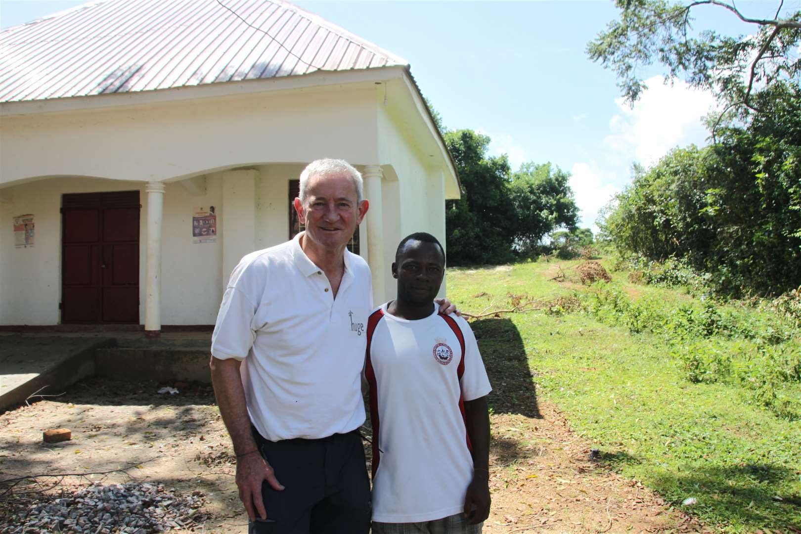 Trustee Richard Batten, along with headmaster of at Nabugabo Community Learning Centre, Vincent, outside the new exam hall
